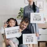Family celebrating adoption with heartfelt signs indoors, filled with love and joy.